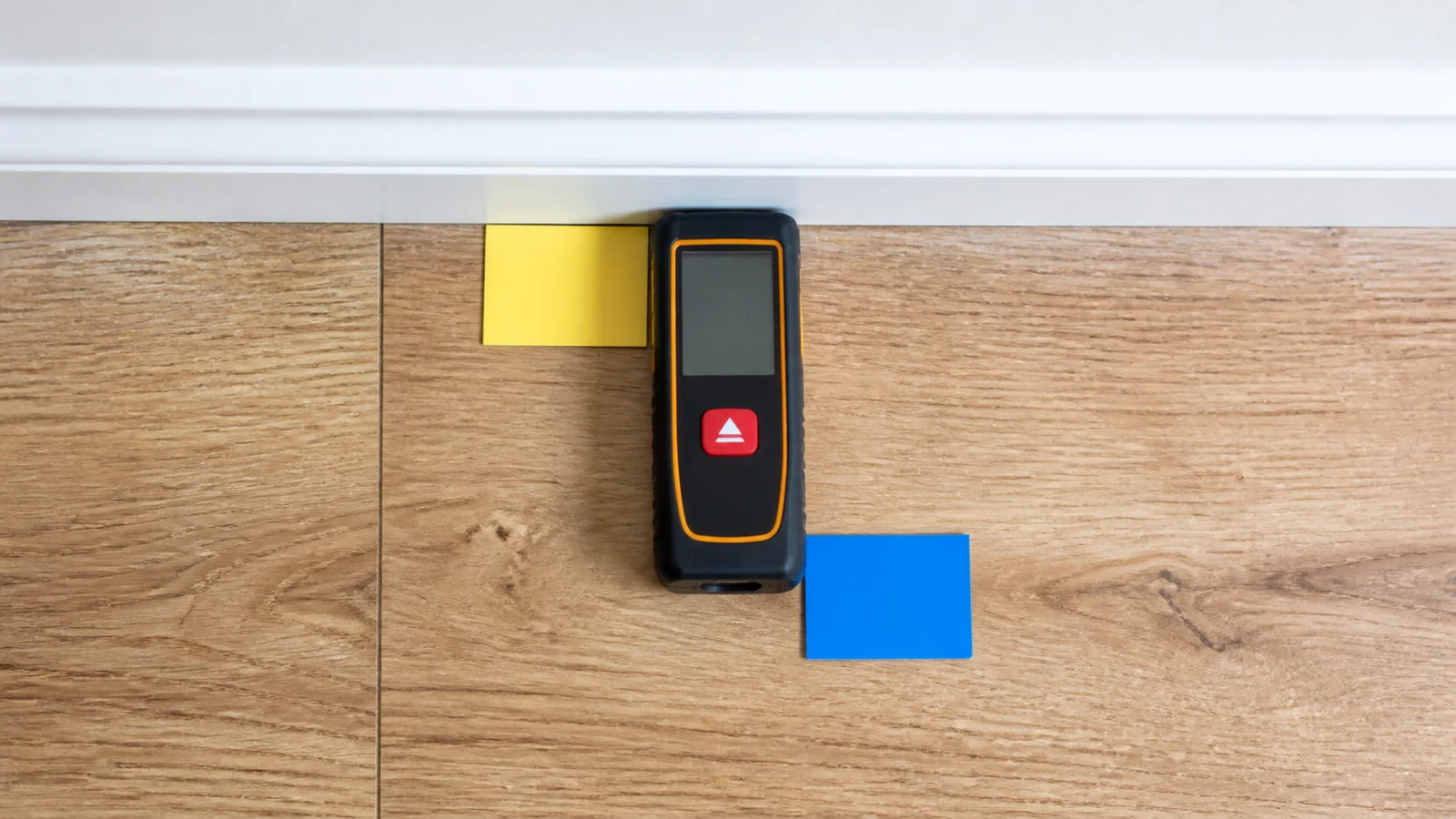 Laser distance meter showing front versus rear measuring reference against a wall